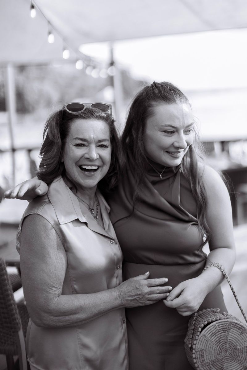 Two women laughing together at an outdoor event, black and white photo